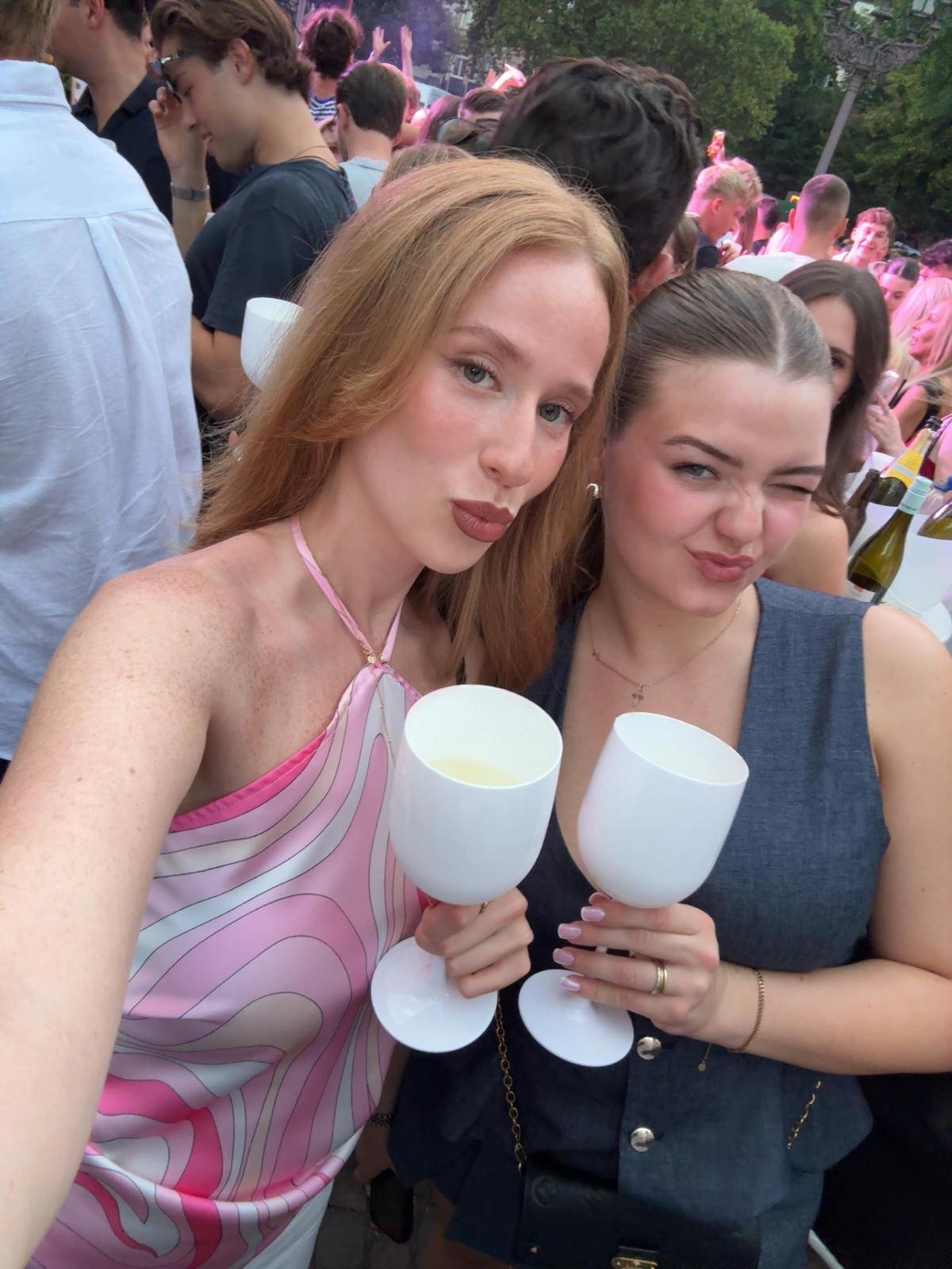 Zwei Gäste stoßen bei einem Open-Air-Event mit weißen Bechern an